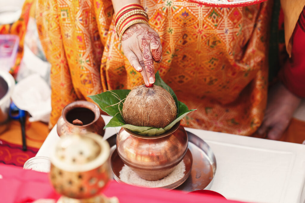 indian woman holds coconut mango leaves put bronze